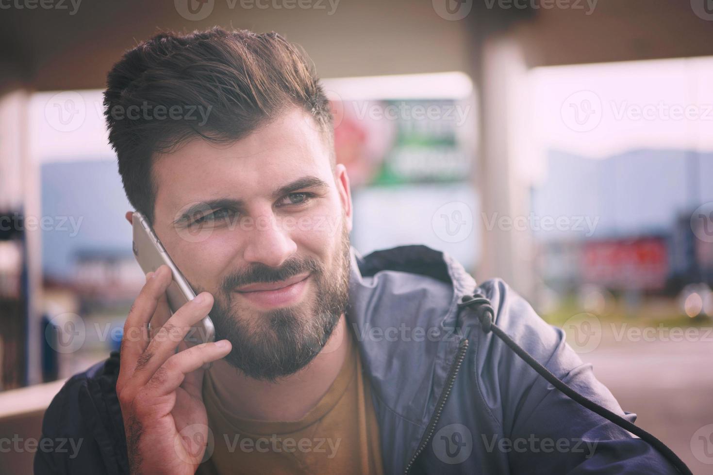 knap jong gewoontjes bedrijf Mens met baard gebruik makend van cel telefoon foto