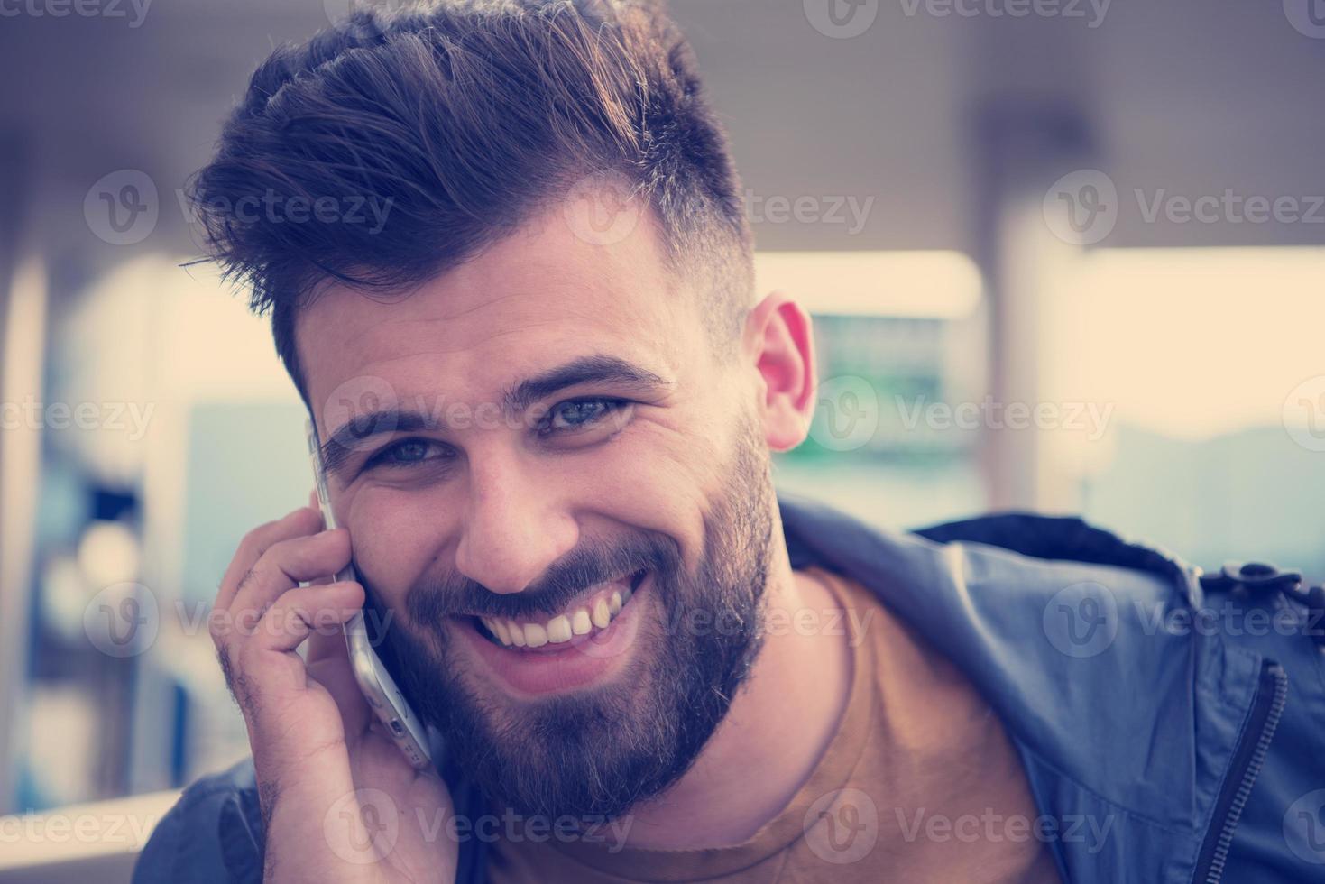 knap jong gewoontjes bedrijf Mens met baard gebruik makend van cel telefoon foto