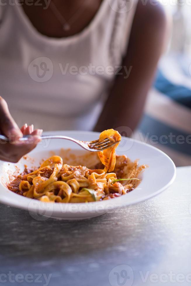 een jonge Afro-Amerikaanse vrouw die pasta eet foto