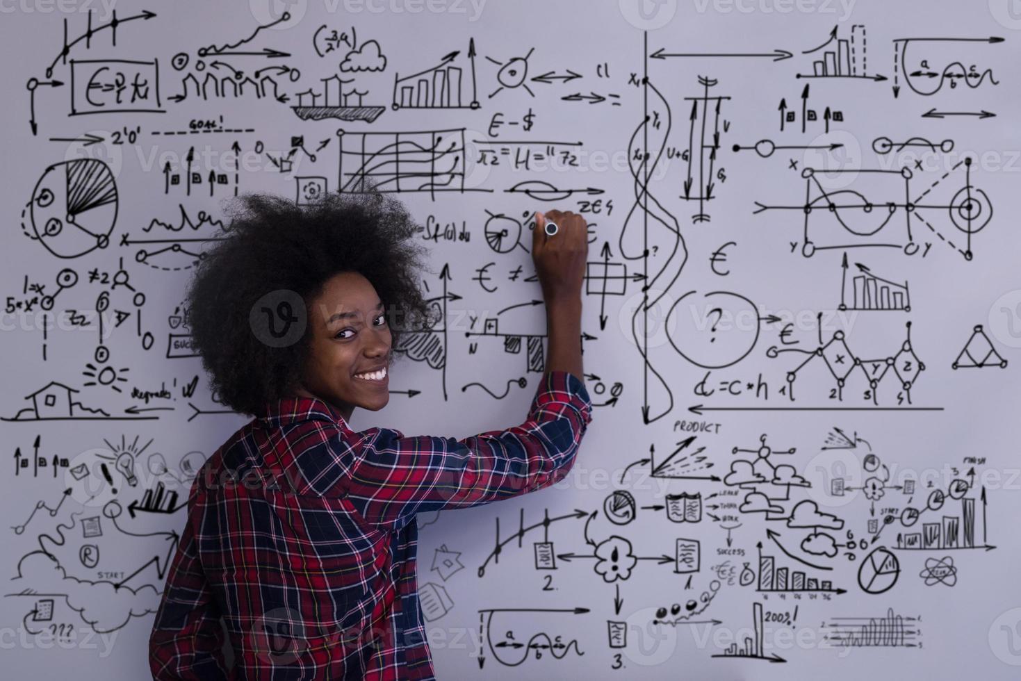 Afro-Amerikaanse vrouw die op een schoolbord in een modern kantoor schrijft foto