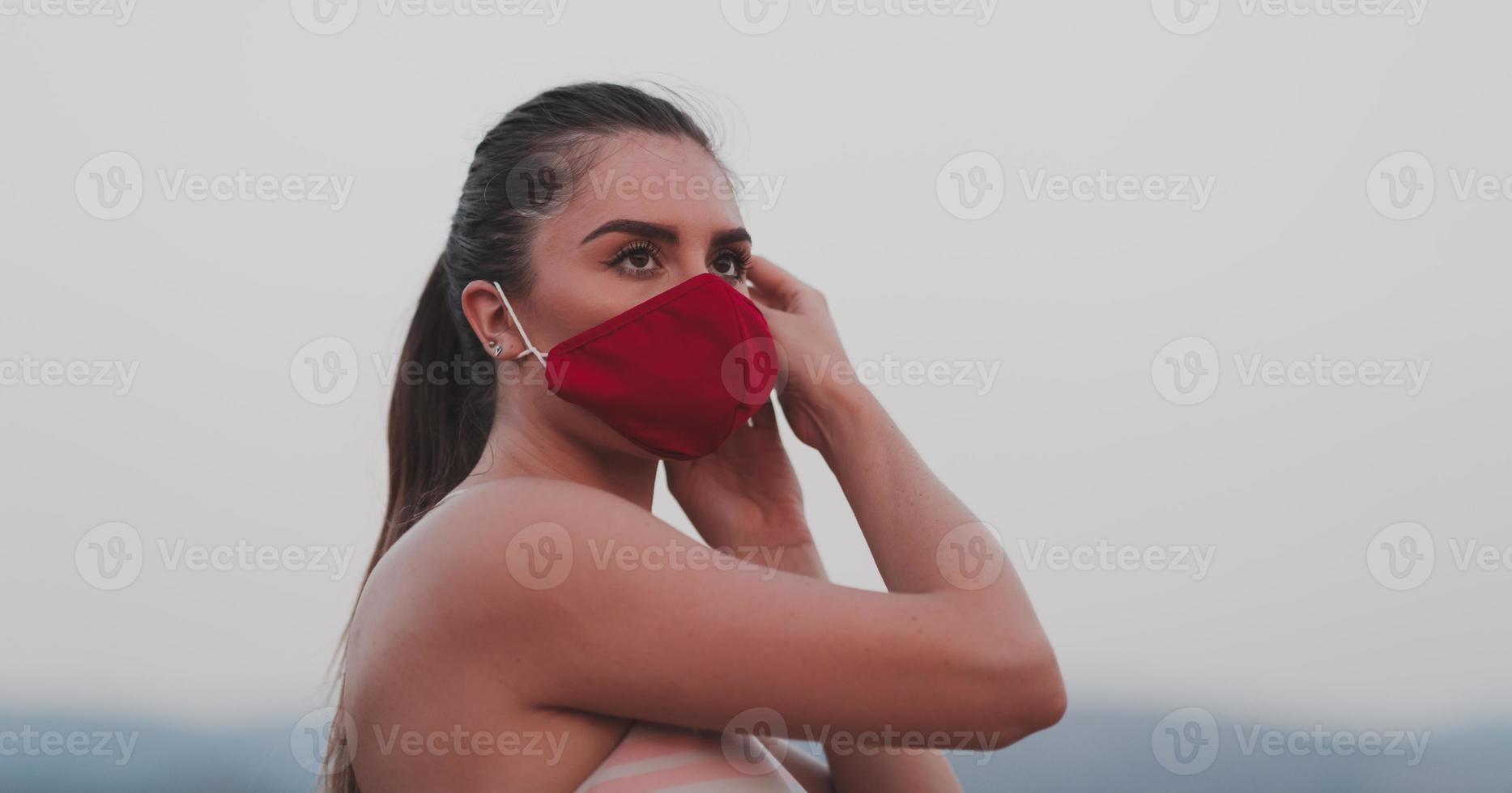 vastbesloten geschiktheid vrouw in kort kleren vervelend rood beschermend gezicht masker rennen buitenshuis in de stad gedurende coronavirus uitbraak. covid 19 en fysiek jogging werkzaamheid sport en geschiktheid. foto