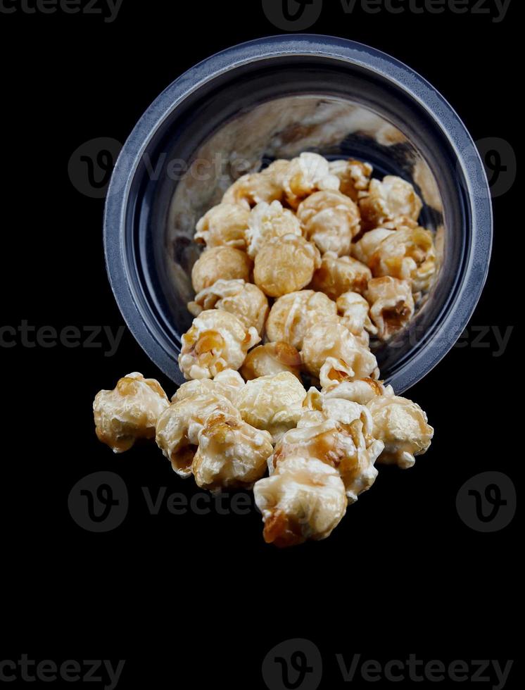 popcorn morsen uit van een plastic glas. isoleren Aan een zwart achtergrond. foto