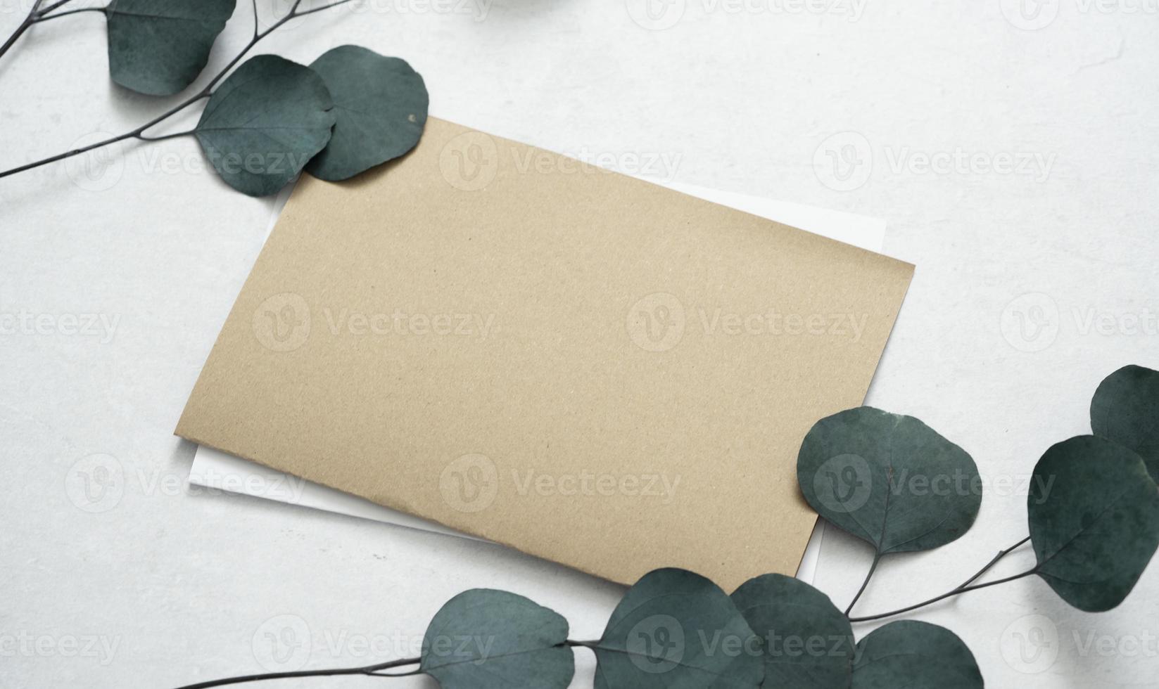 mockup voor een brief of een huwelijksuitnodiging met bladeren van eucalyptustakken. foto