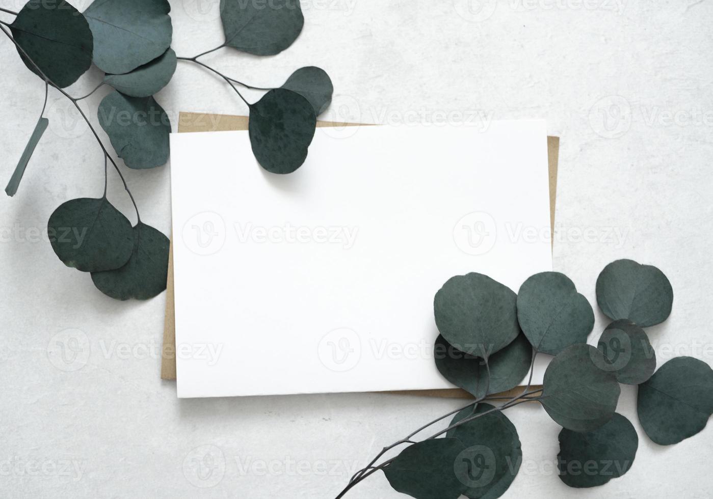 mockup voor een brief of een huwelijksuitnodiging met bladeren van eucalyptustakken. foto