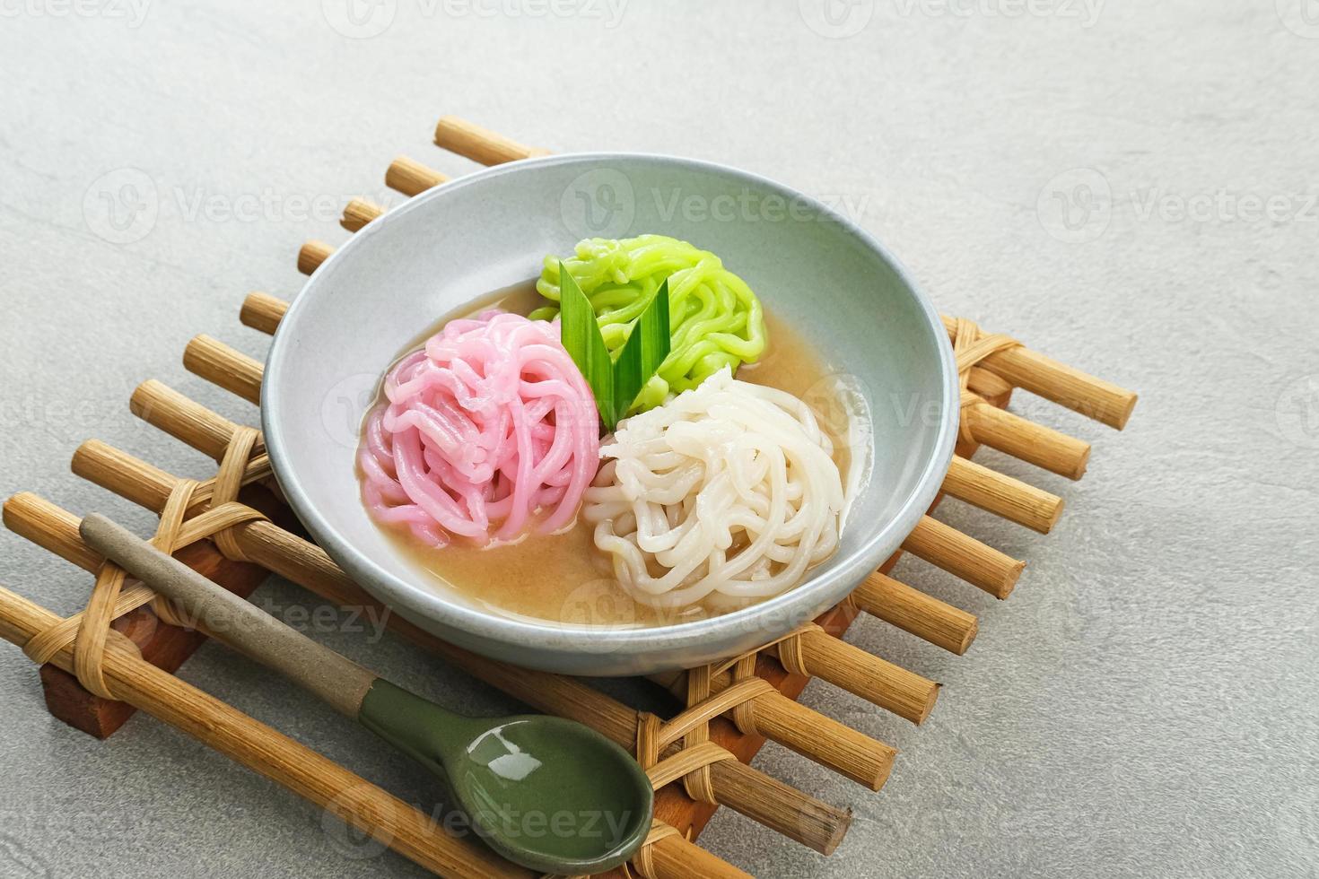 kue putu mayang is traditioneel Indonesisch tussendoortje gemaakt van rijst- meel strengen gekruld omhoog in een bal, geserveerd met kokosnoot melk en palm suiker. geselecteerd focus. foto