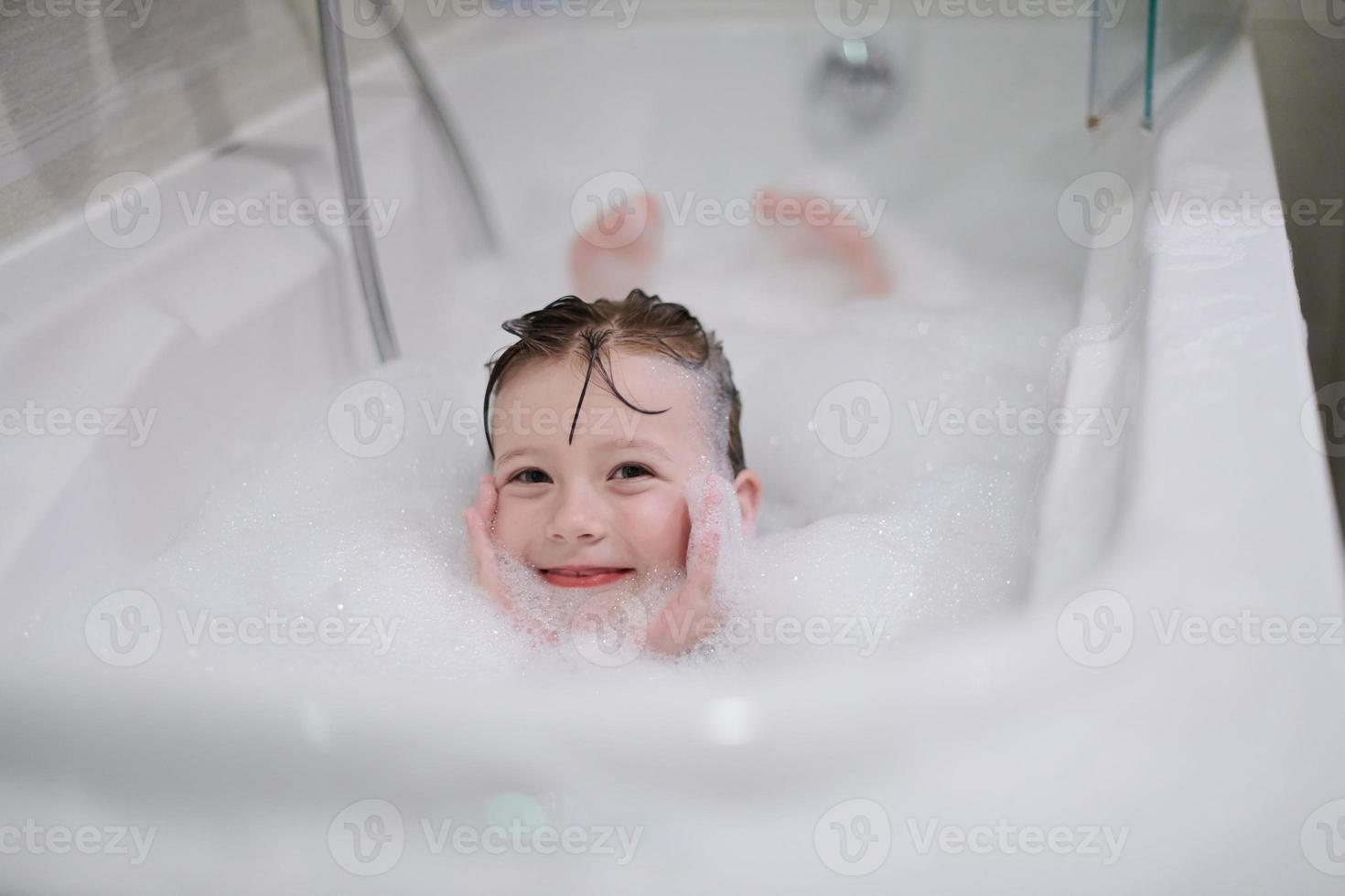 weinig meisje in bad spelen met zeep schuim foto