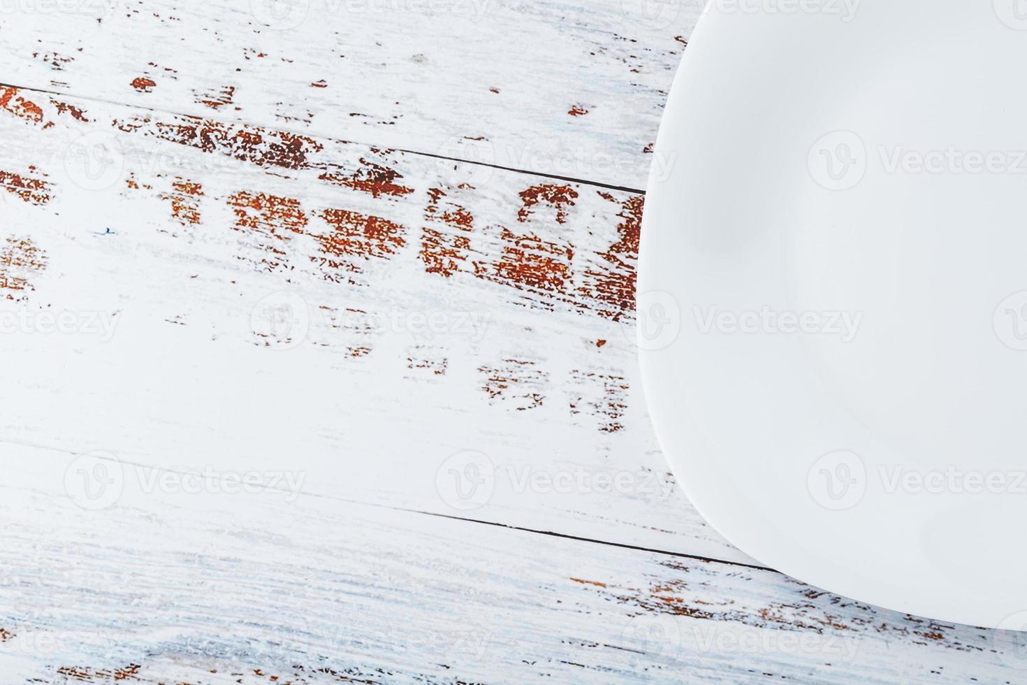 een leeg ronde wit bord Aan een blauw houten tafel. foto