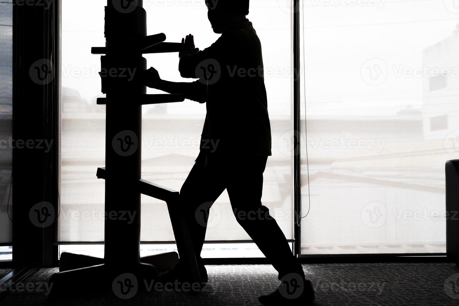 silhouet van een vechter vleugel chun en houten dummy Aan een achtergrond. vleugel chun kung fu zelf verdediging foto