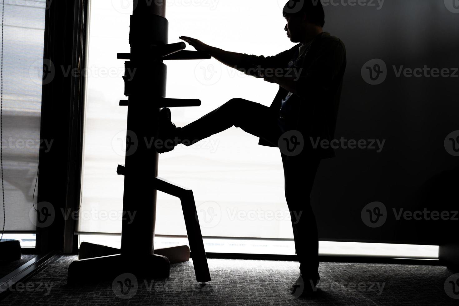 silhouet van een vechter vleugel chun en houten dummy Aan een achtergrond. vleugel chun kung fu zelf verdediging foto