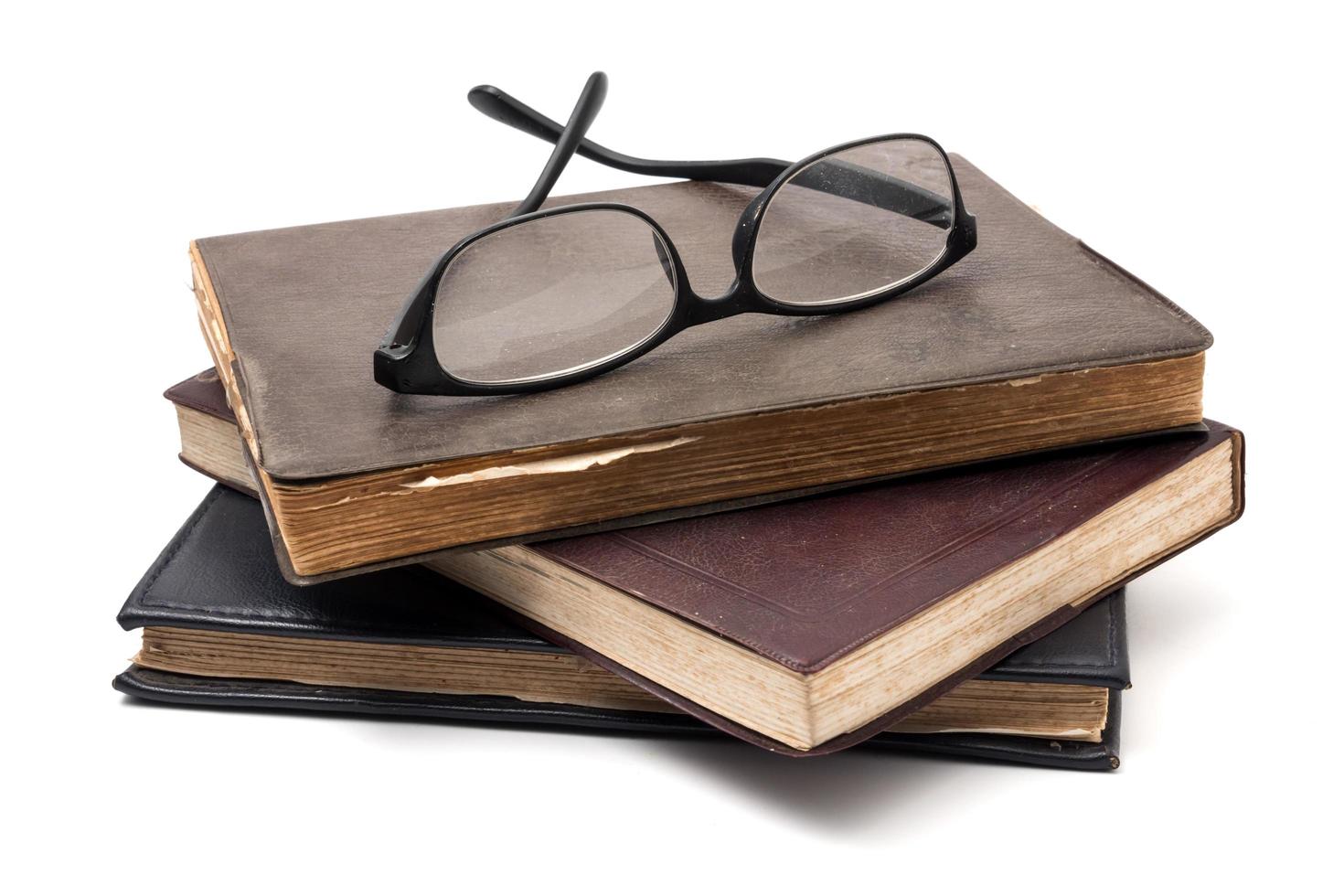 een stack van oud boeken met bril Aan een wit achtergrond. foto
