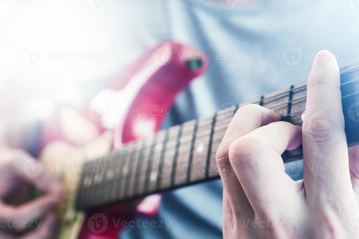 dichtbij omhoog van mannetje handen spelen elektrisch gitaar, gloed van de zonlicht, selectief focus foto