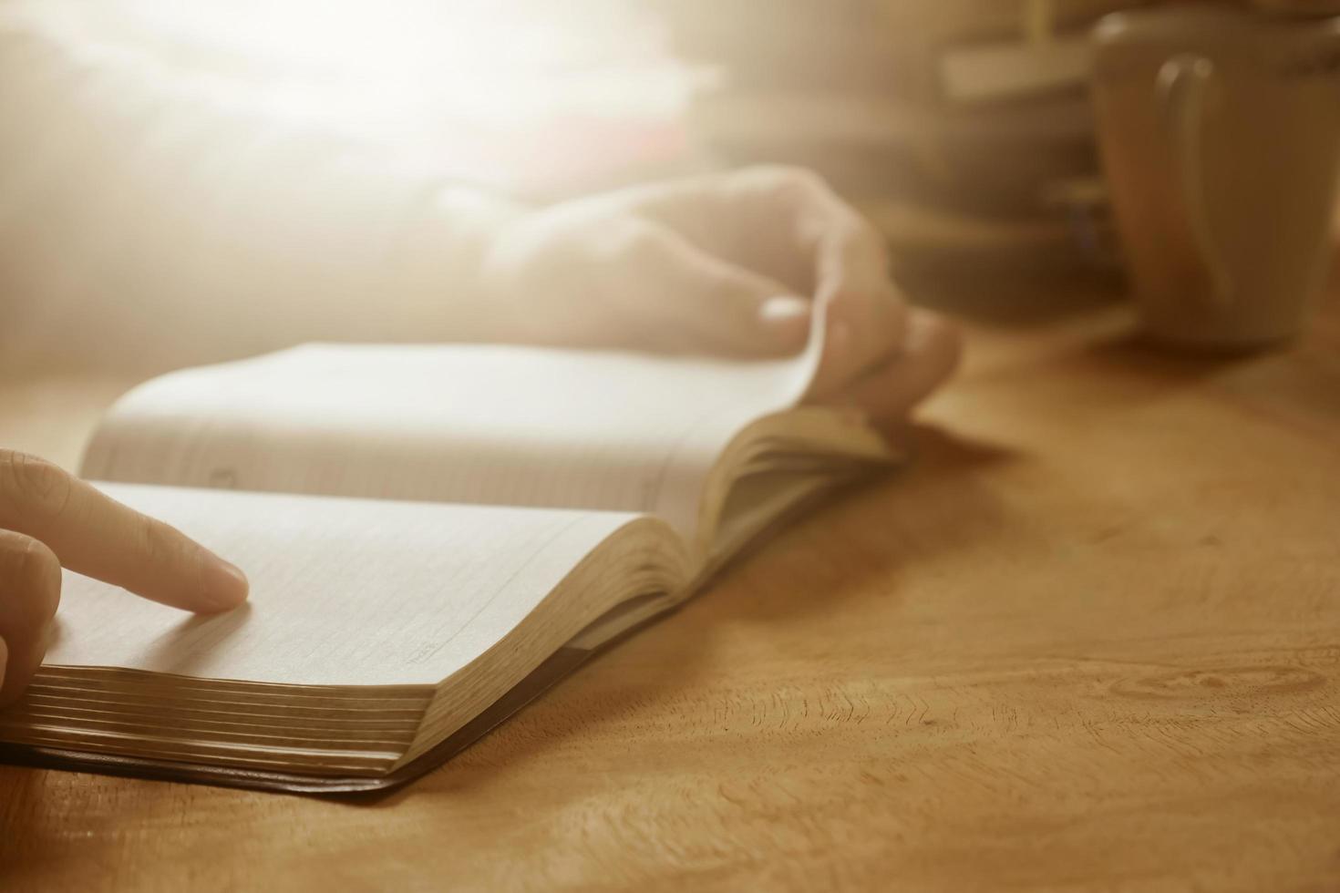 dichtbij omhoog van mannetje handen Open een boek Aan houten bureau, zacht focus, gloed zon licht, vintage toon. foto