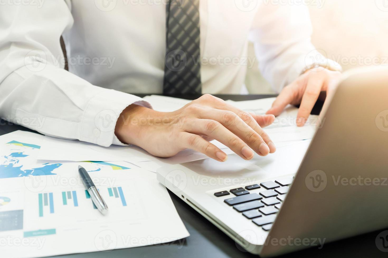 dichtbij omhoog van zakenman analyseren investering grafieken en gebruik makend van laptop Aan de bureau. foto