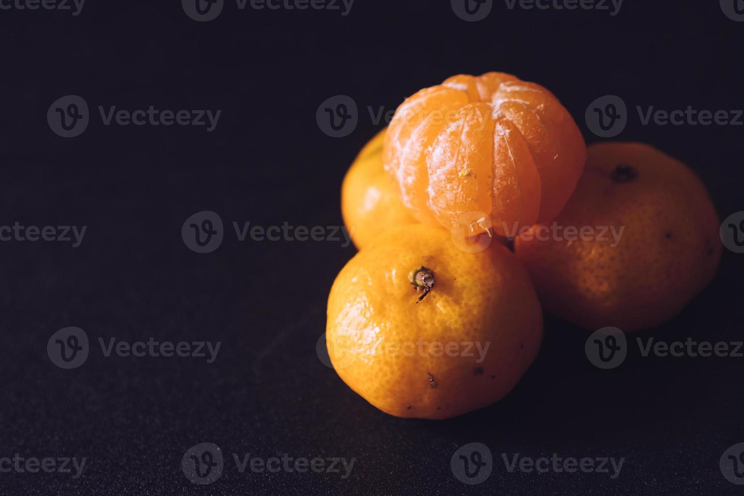 dichtbij omhoog van vers mandarijnen, oranje fruit Aan donker achtergrond. foto