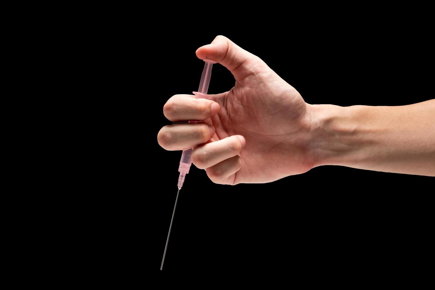 mannetje hand- Holding medisch gereedschap injectiespuit Aan een zwart achtergrond. foto