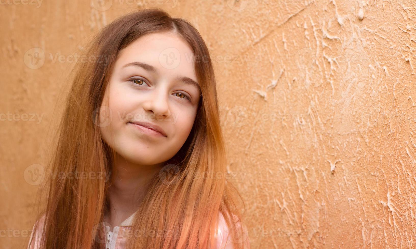 een tiener- meisje in een roze jasje Aan een beige achtergrond. portret van een mooi meisje. foto