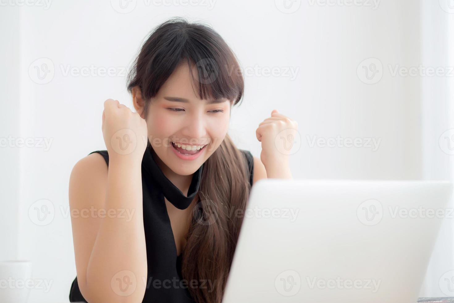 mooi portret Aziatische jonge vrouw glimlach online laptopcomputer werken met gelukkig tevreden zittend op bureau kantoor, meisje met behulp van notebook met opgewonden en blij, business en succes concept. foto