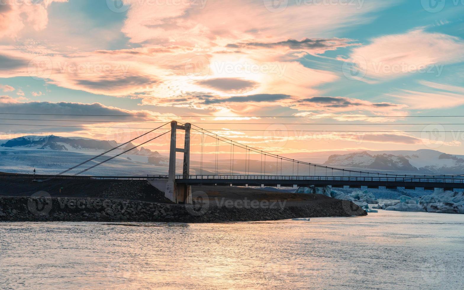 mooi zonsondergang over- suspensie brug Aan jokulsarlon glaciaal rivier- lagune met ijsberg drijvend in zuidelijk van vatnajokull nationaal park Bij IJsland foto