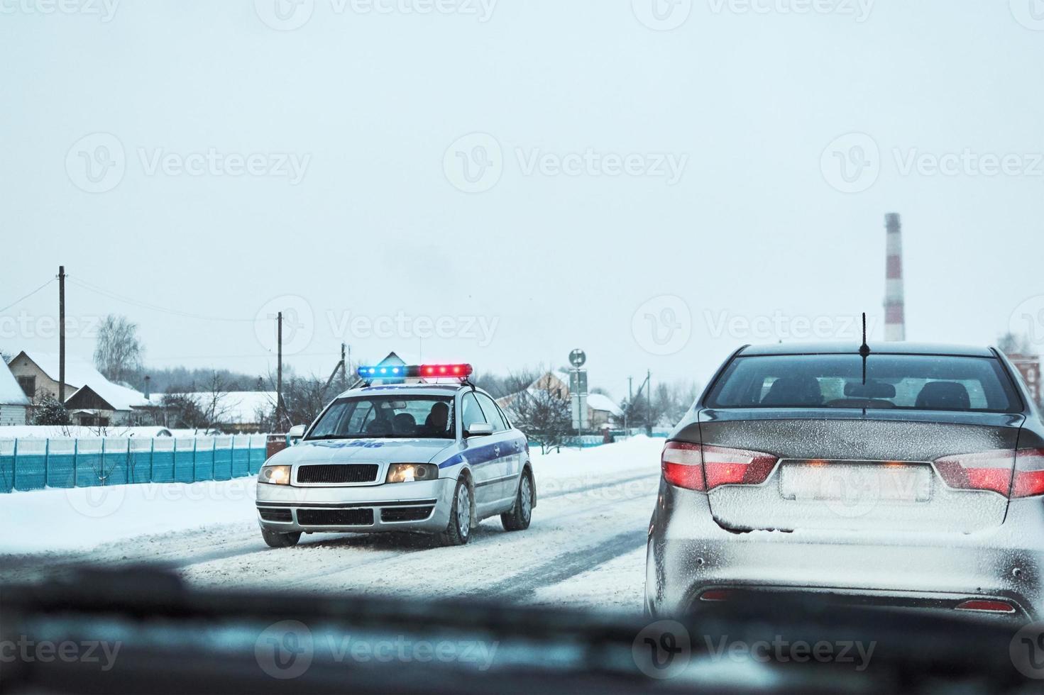 Politie auto met rood en blauw flshaer lichten gestopt auto Aan winter besneeuwd weg foto