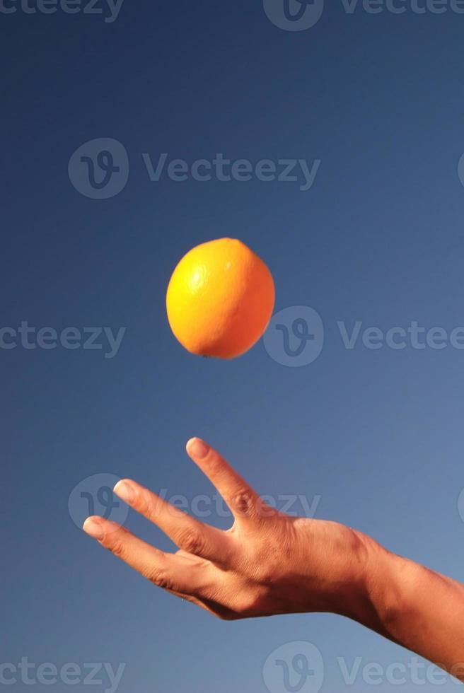 vrouw hand- balanceren oranje in lucht foto