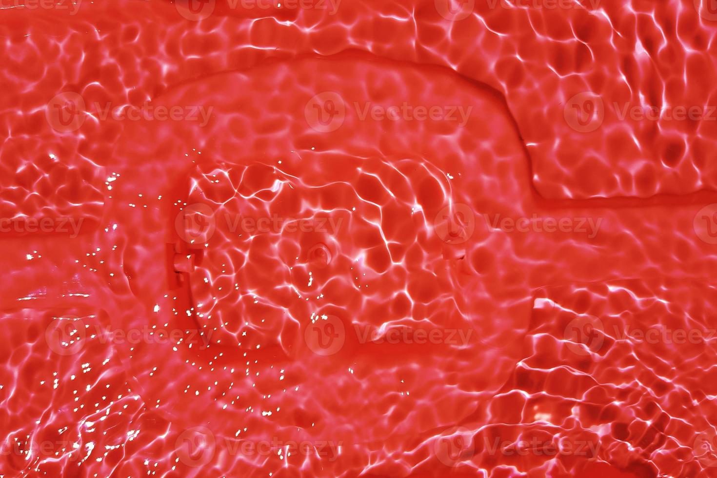 onscherp wazig transparant rood roze gekleurde Doorzichtig kalmte water oppervlakte structuur met spatten en bubbel. modieus abstract natuur achtergrond. water Golf in zonlicht met kopiëren ruimte. roze water laten vallen kleur foto