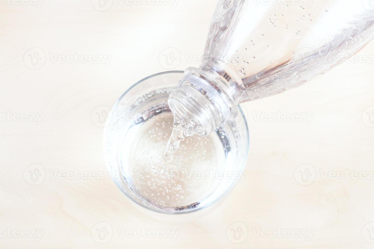 gieten water van Doorzichtig plastic fles in glas foto