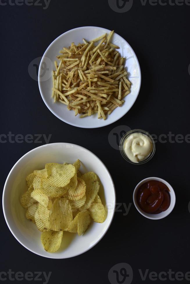 heerlijk aardappel chips met sauzen Aan een zwart achtergrond. voorafje van aardappel chips met saus. snel voedsel Aan een zwart achtergrond. foto