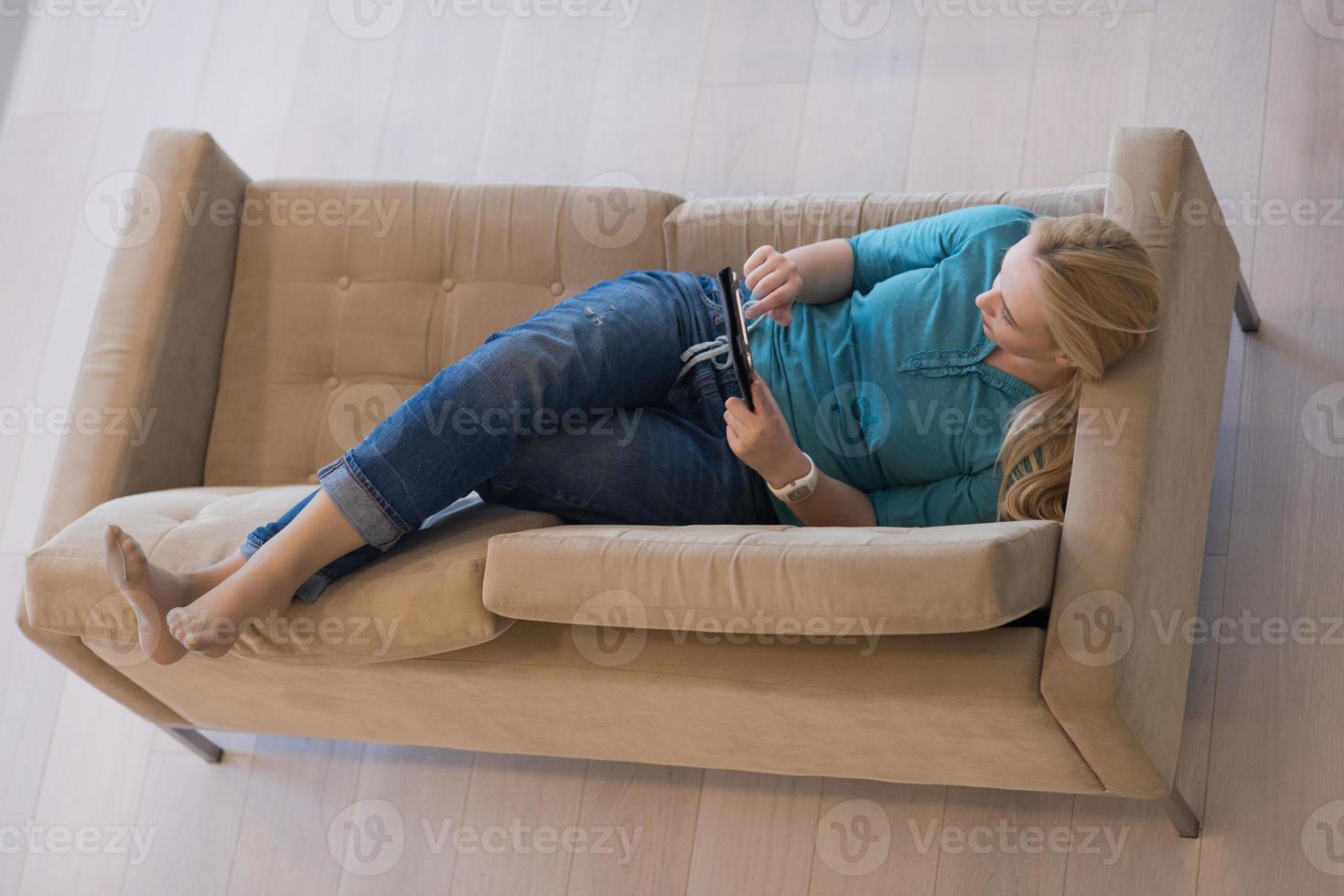 vrouw Aan sofa gebruik makend van tablet computer foto