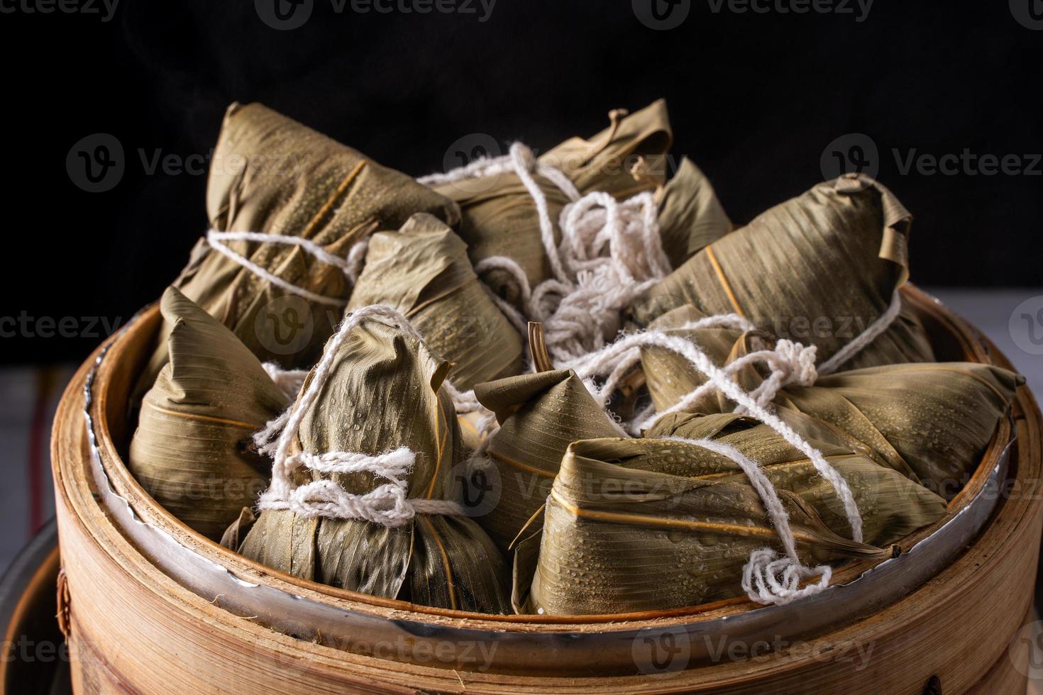 rijst- knoedel, zongzi - bundel van Chinese traditioneel gekookt voedsel Aan houten tafel over- zwart achtergrond, concept van draak boot festival, dichtbij omhoog, kopiëren ruimte foto
