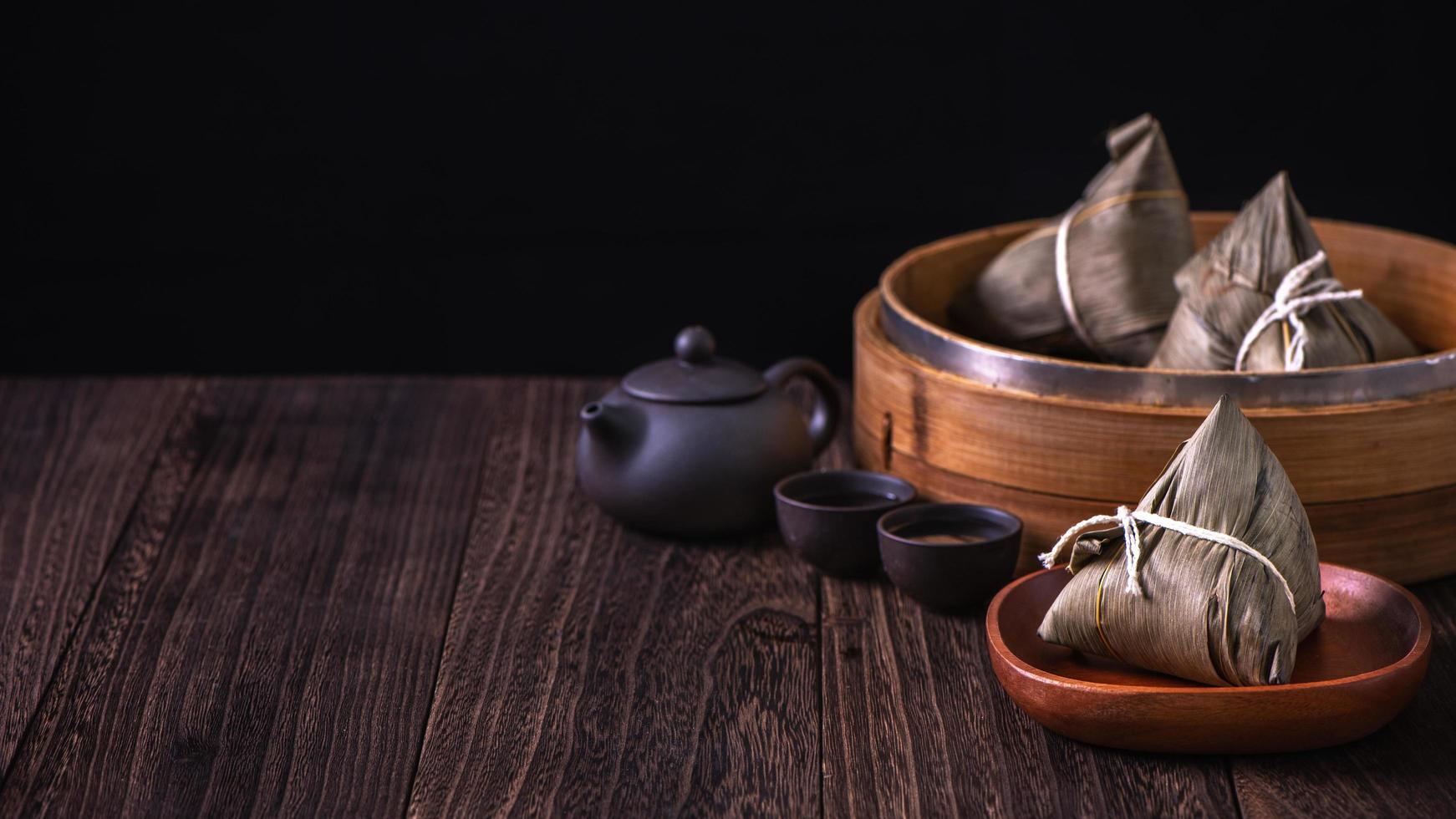 zongzi - Chinese rijst- knoedel zongzi in een stoomboot Aan houten tafel zwart retro achtergrond voor draak boot festival viering, dichtbij omhoog, kopiëren ruimte. foto