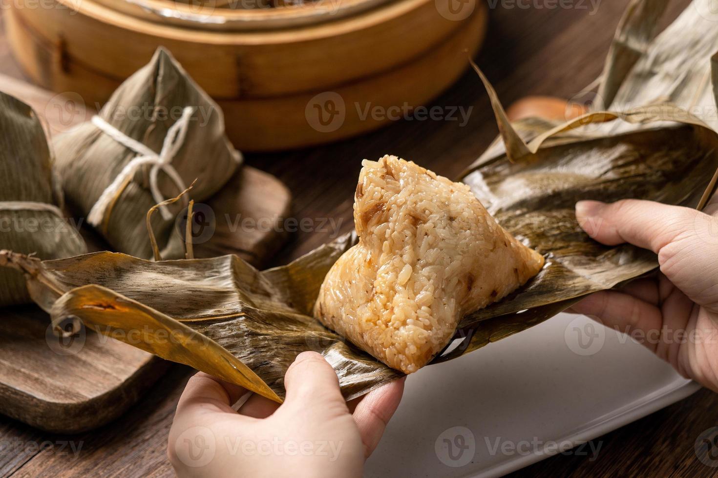 draak boot festival voedsel - rijst- knoedel zongzi, jong Aziatisch vrouw aan het eten Chinese traditioneel voedsel Aan houten tafel Bij huis viering, dichtbij omhoog foto