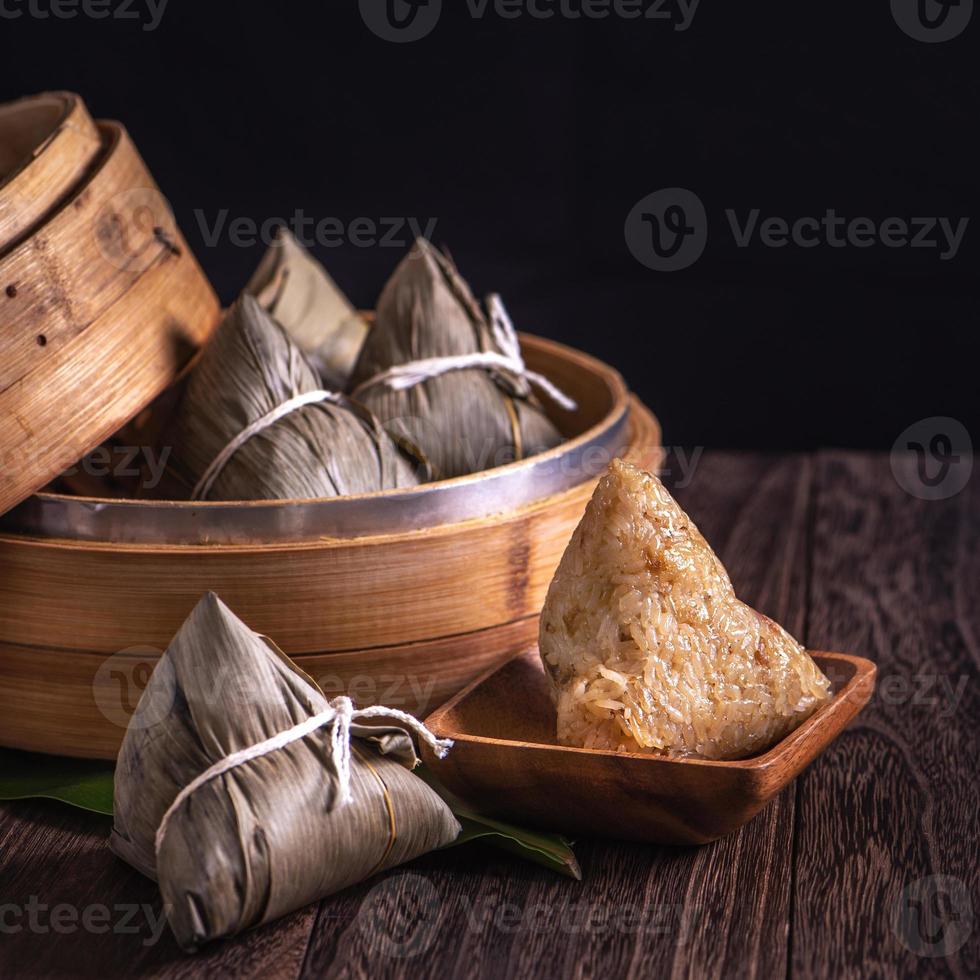 rijst knoedel, zongzi - drakenboot festival, stelletje traditioneel Chinees gekookt voedsel in stoomboot op houten tafel op zwarte achtergrond, close-up, kopieer ruimte foto