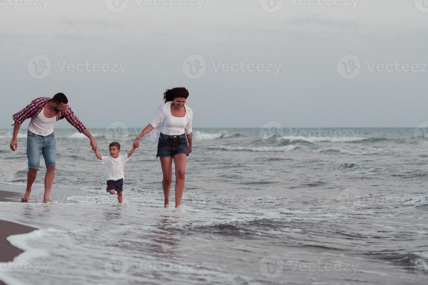 de familie geniet hun vakantie net zo ze wandelen de zanderig strand met hun zoon. selectief focus foto