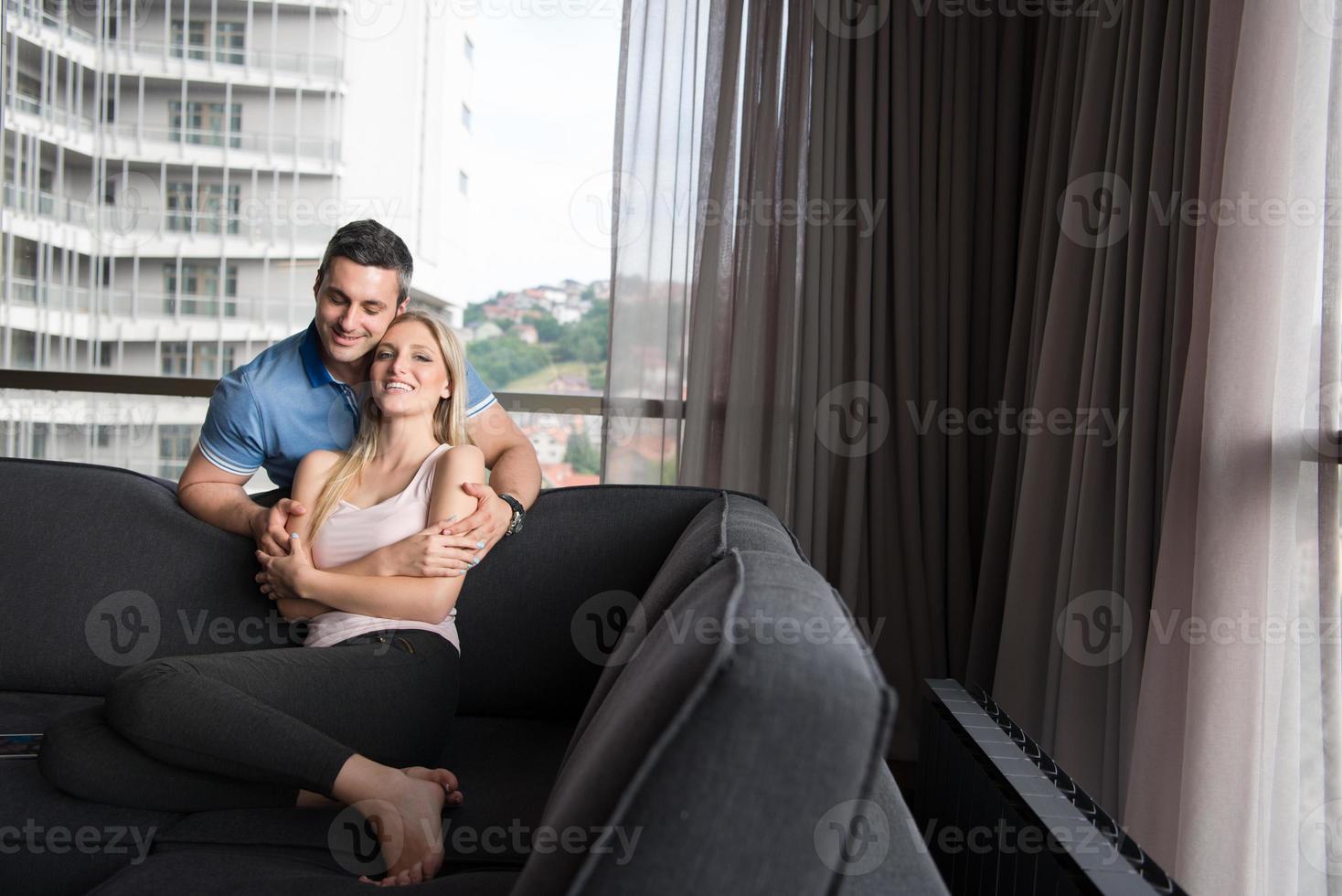 jong knap paar knuffelen Aan de sofa foto