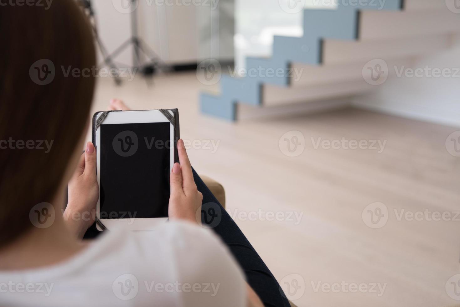 vrouw zittend Aan sofa met tablet computer foto