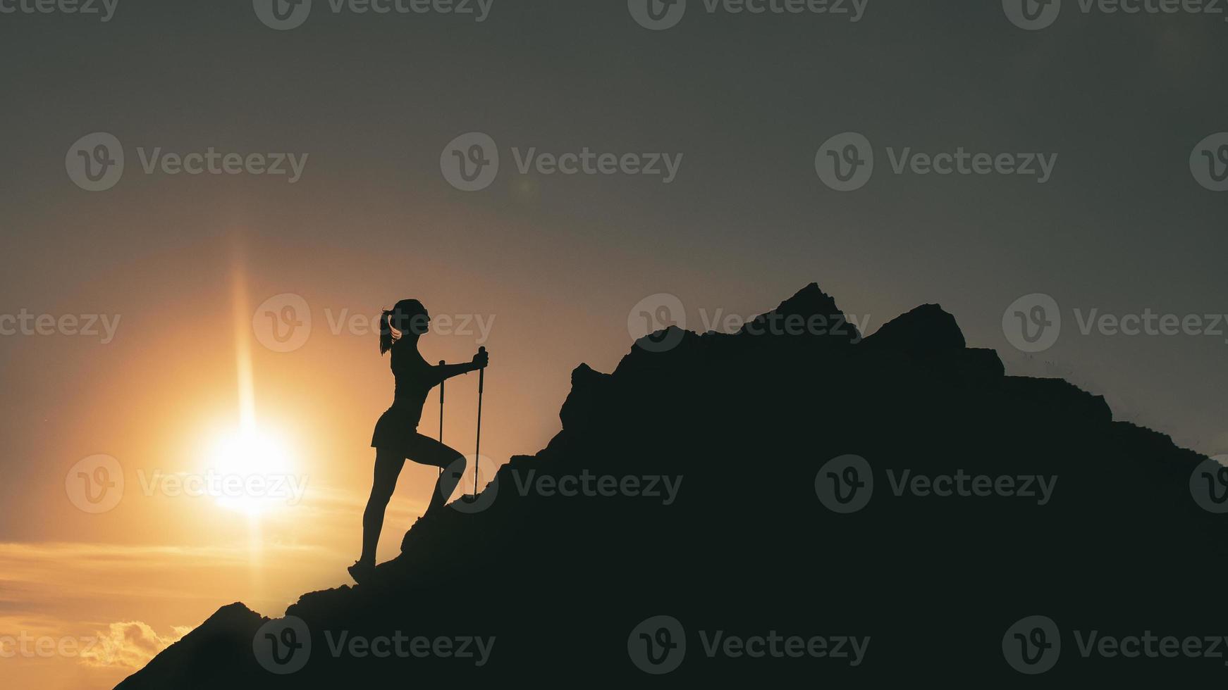 vrouw klimt tussen rotsen in een kleurrijk berg zonsondergang foto