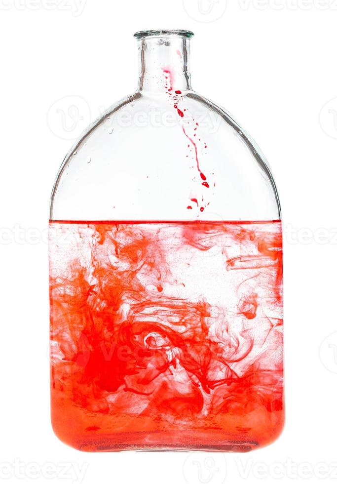 rood kleurstof lost op in water in glas fles geïsoleerd foto