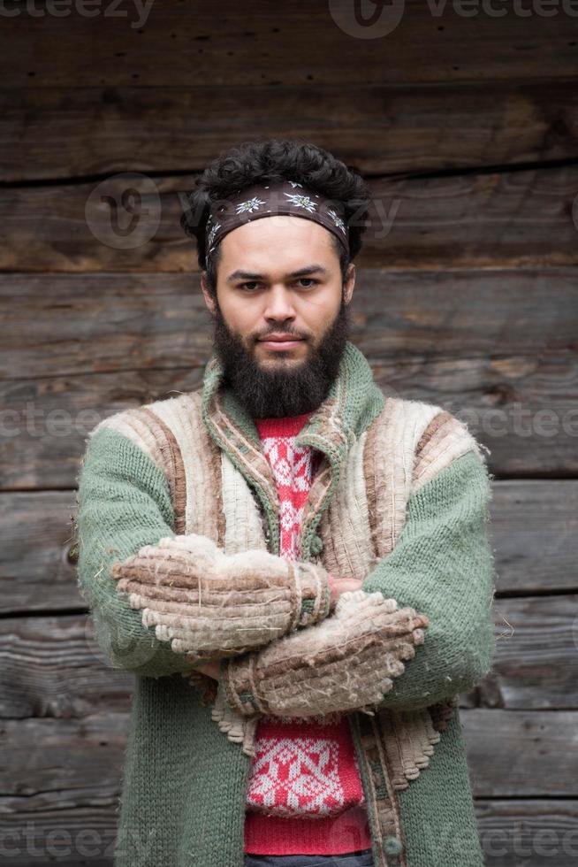 portret van jong hipster in voorkant van houten huis foto