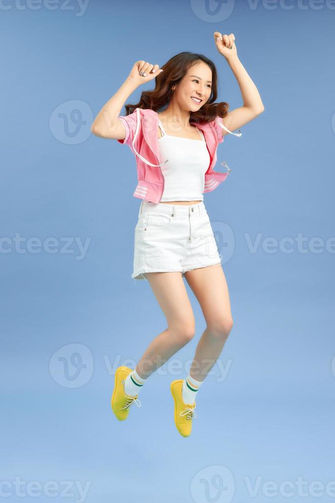 vrolijk hipster meisje springend met handen verspreiding breed over- achtergrond. jong vrouw in springen. foto