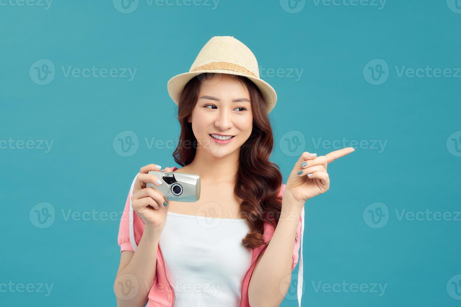 expressief portret van een mooi jong Aziatisch vrouw in de studio Aan een blauw achtergrond met een camera in zijn handen foto