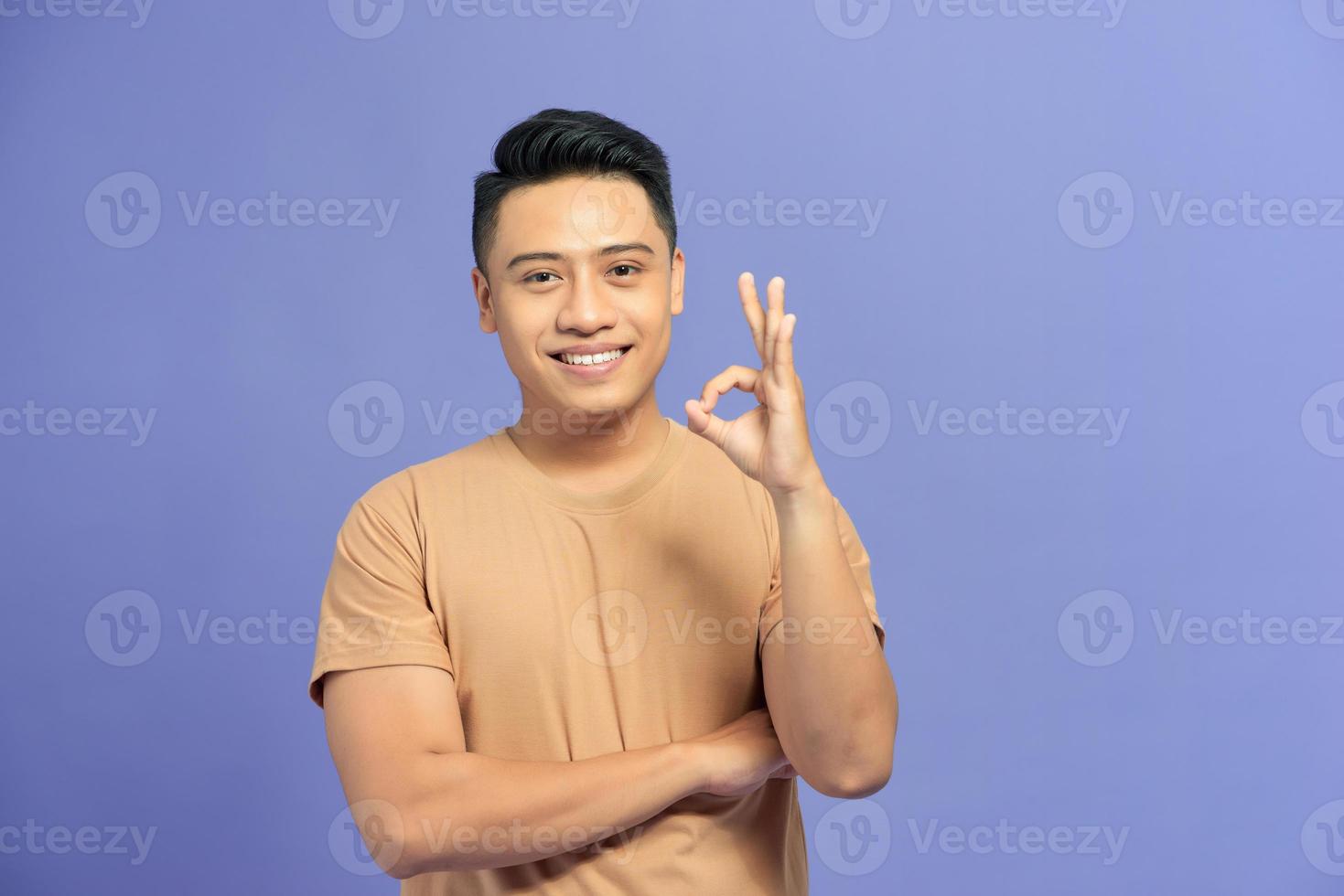 portret van een gelukkig jong Mens tonen OK gebaar en op zoek Bij camera geïsoleerd over- kleur achtergrond foto