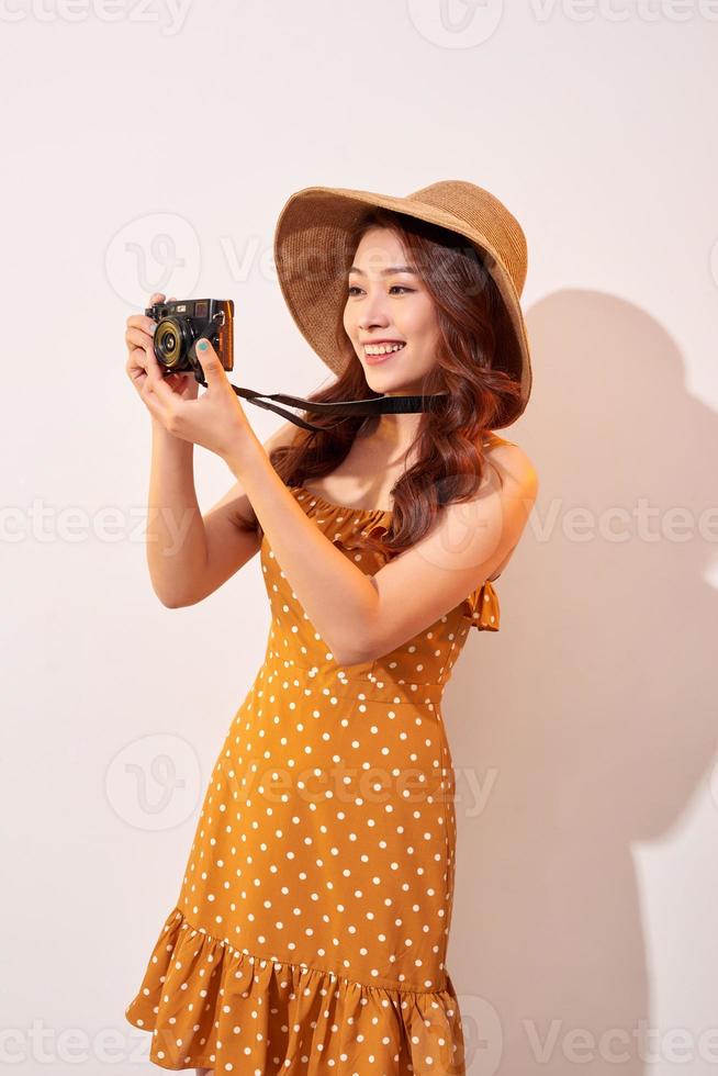 beeld van jong fotograaf vrouw geïsoleerd over- beige achtergrond muur Holding camera. foto