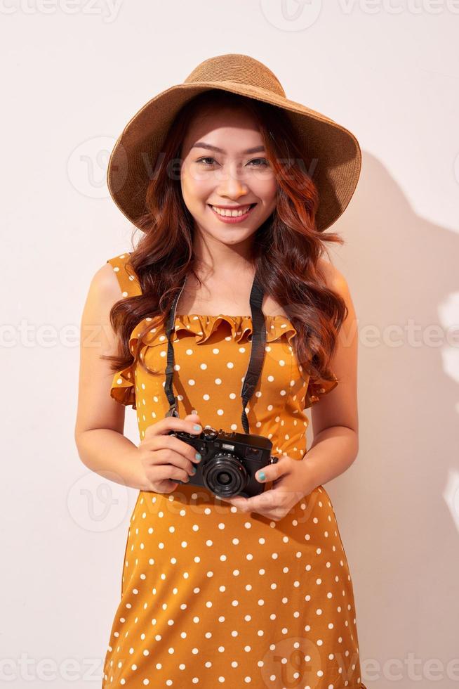 beeld van jong fotograaf vrouw geïsoleerd over- beige achtergrond muur Holding camera. foto