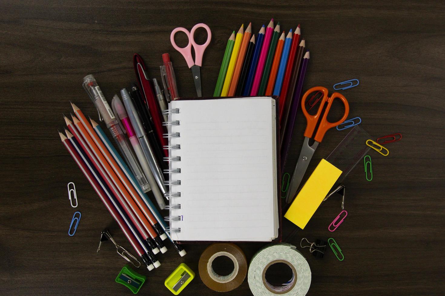 boek in de centrum met kleur potloden en onderwijs elementen, terug naar school- concepten Aan donker hout achtergrond. gebruikt in poster, brochures ontwerp foto