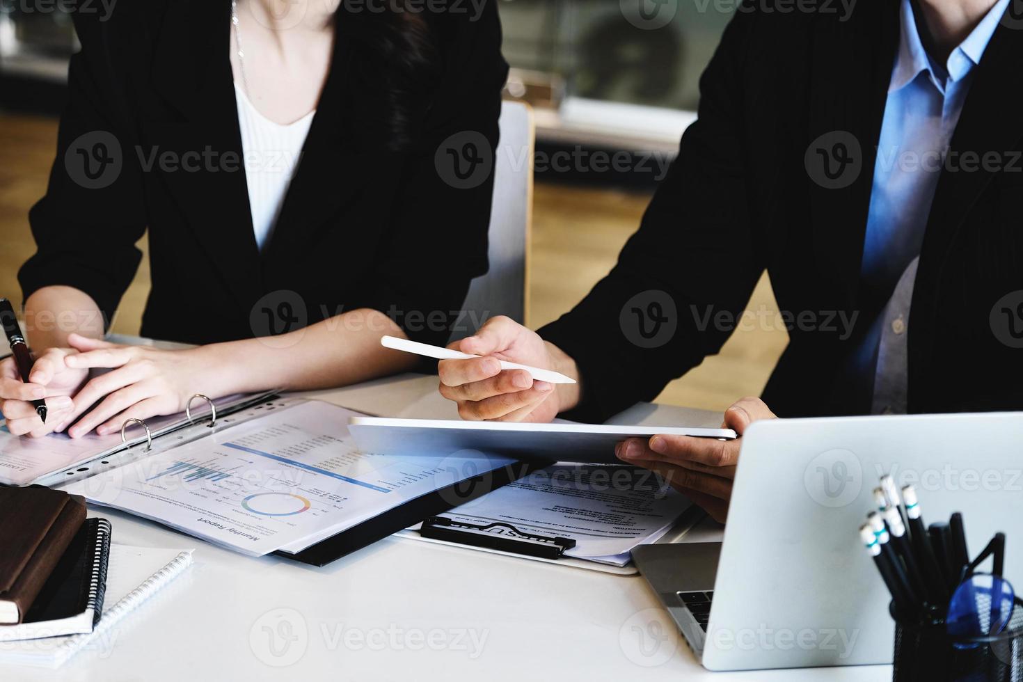 Bij de overleg, een mannetje adviseur toepassingen een pen naar punt Bij een tablet naar leg uit de winst herstructurering naar vrouw bedrijf eigenaren. foto