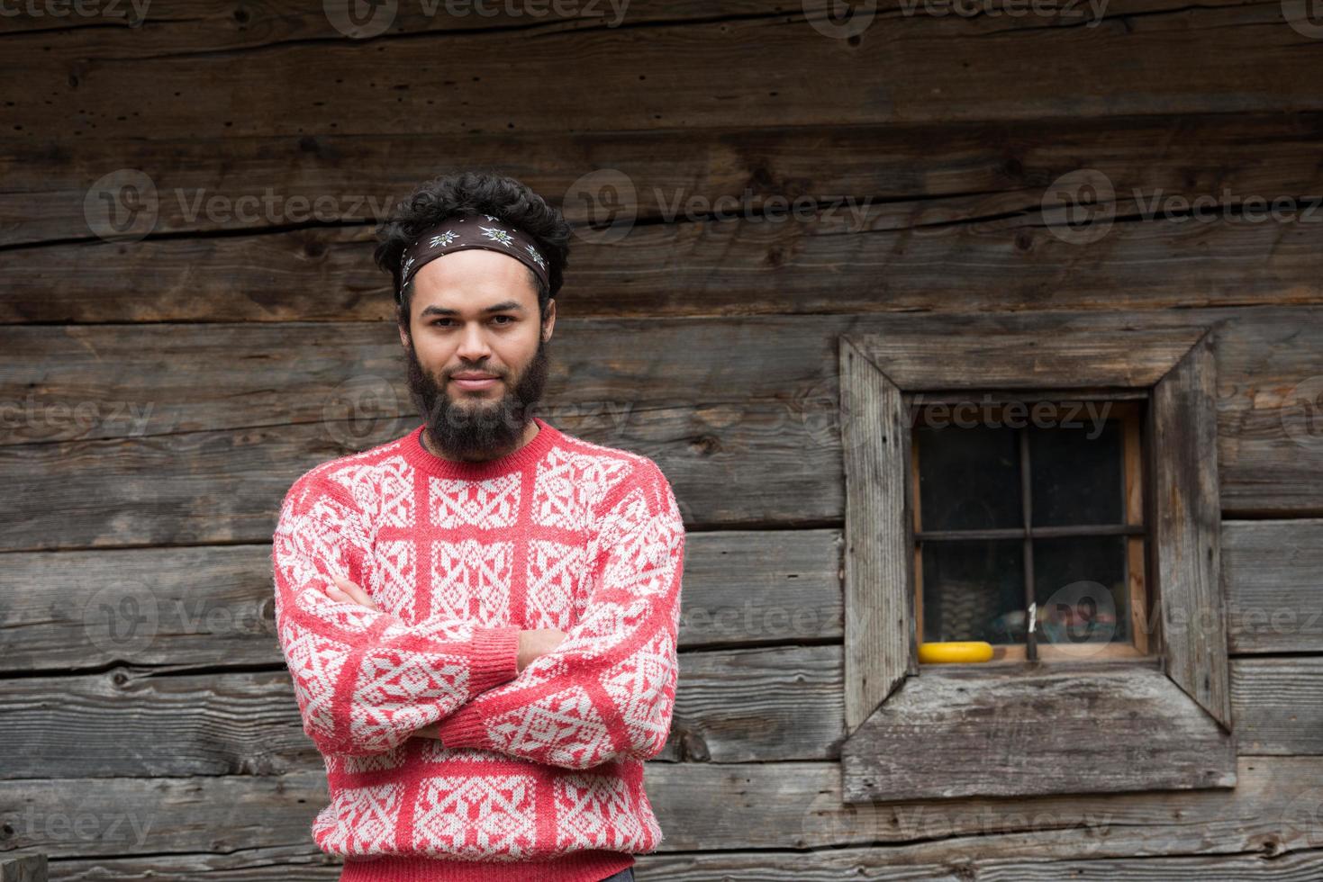 portret van jong hipster in voorkant van houten huis foto