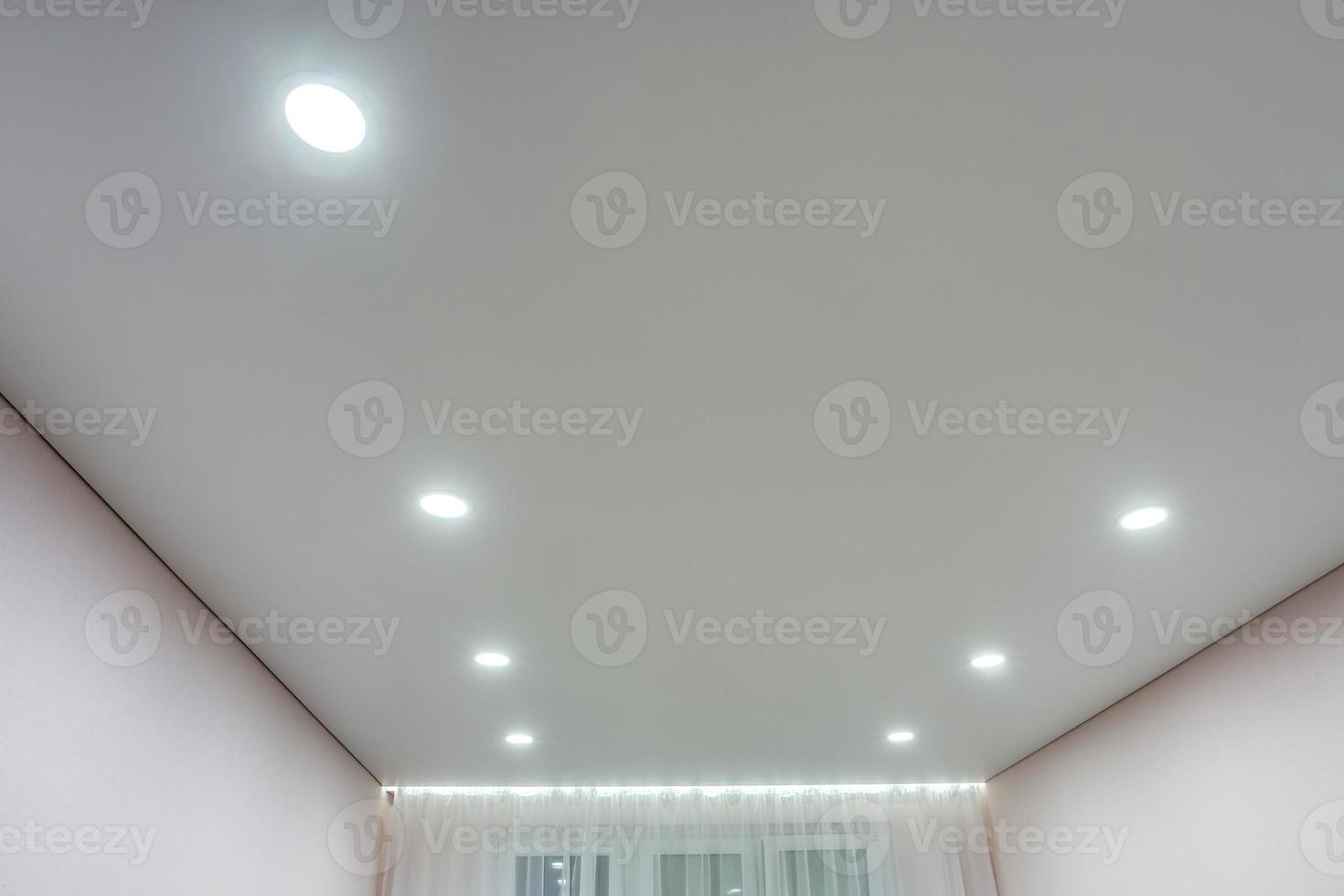 verlaagd plafond met halogeenspots lampen en gipsplaten constructie in lege ruimte in appartement of huis. spanplafond wit en complexe vorm. foto