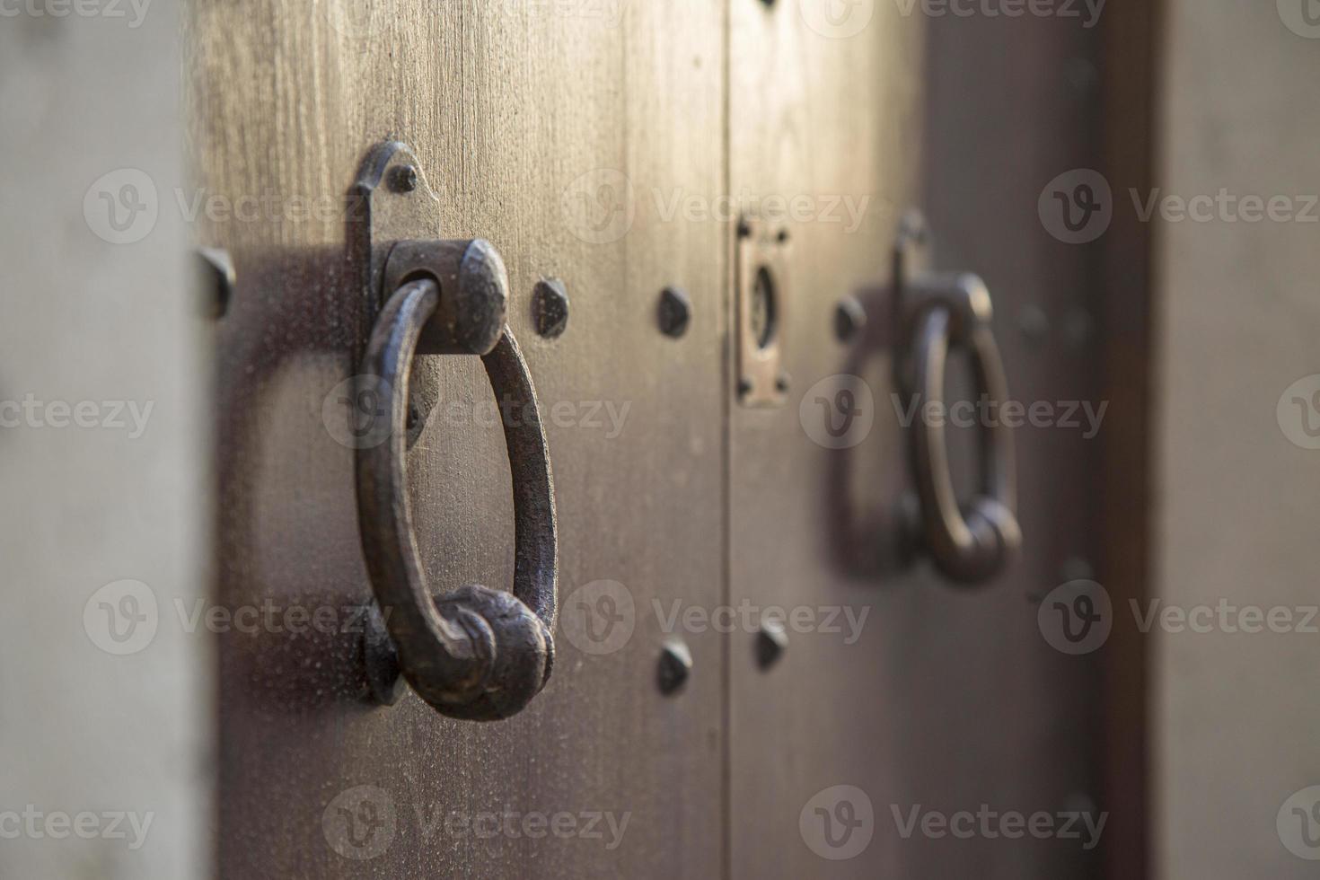 oud houten deuren met ringen en oubollig wijnoogst staal klopper omgaan met dichtbij omhoog in Italië. foto