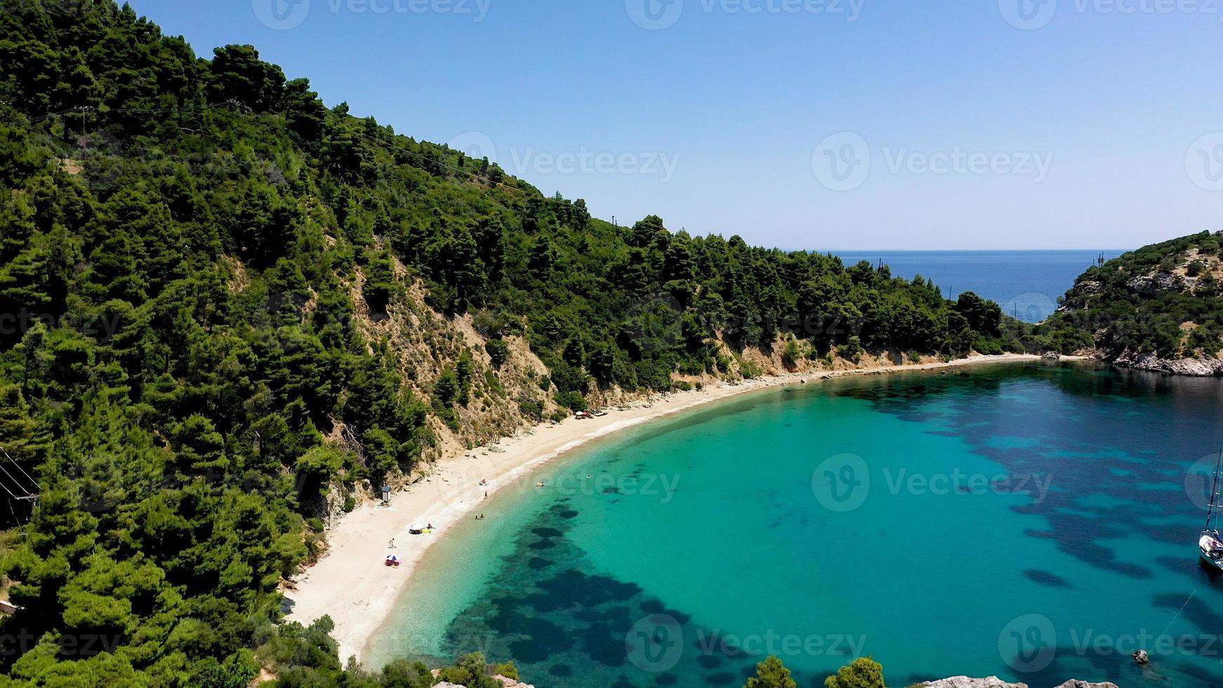 drone-uitzichten vanuit de lucht over een rotsachtige kustlijn, kristalhelder Egeïsch zeewater, toeristische stranden en veel groen op het eiland Skopelos, Griekenland. een typisch beeld van veel vergelijkbare Griekse eilanden. foto