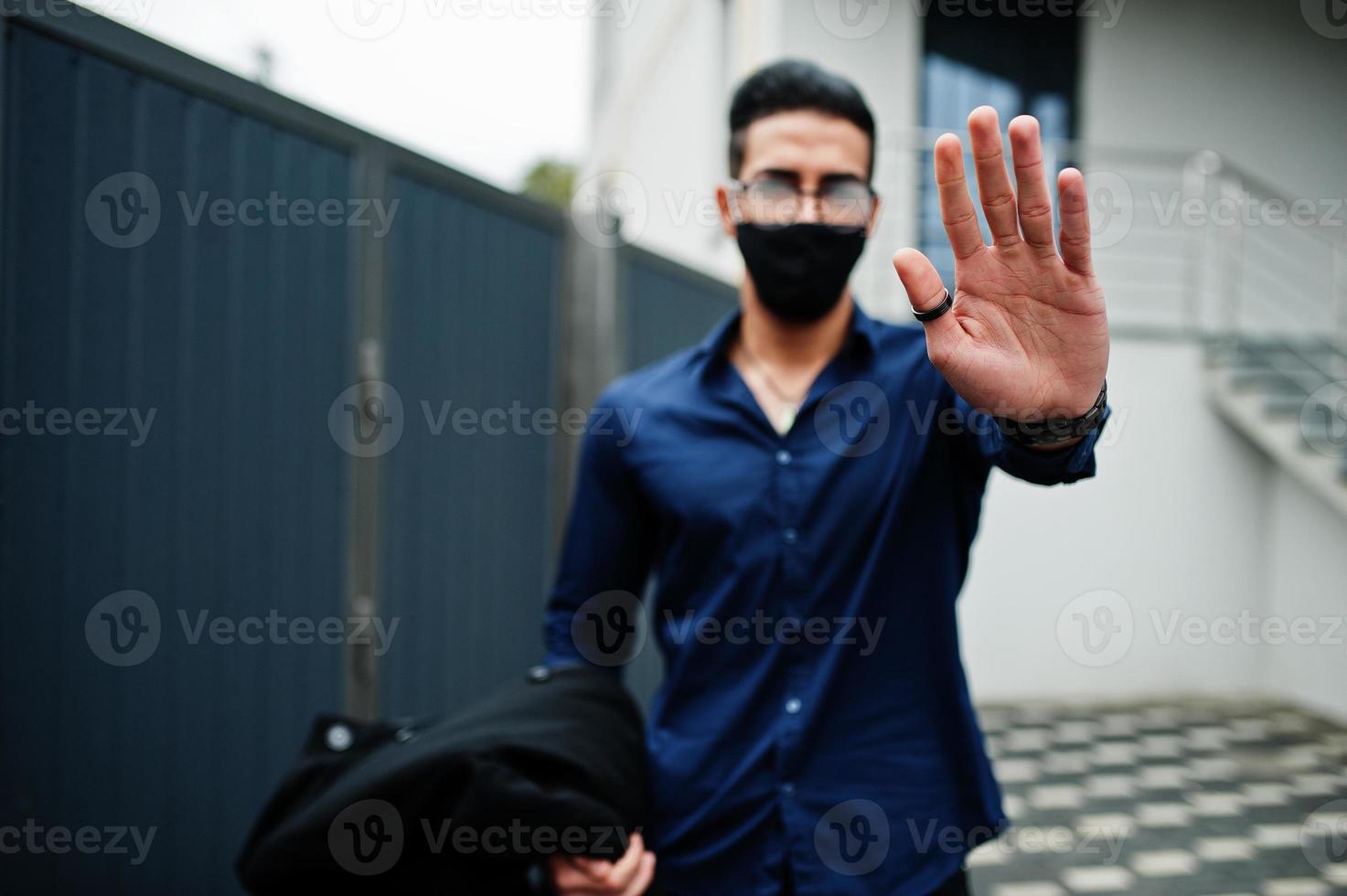midden- oostelijk ondernemer slijtage zwart gezicht masker en bril tonen hou op teken door hand. nieuw normaal leven na coronavirus pandemie. foto